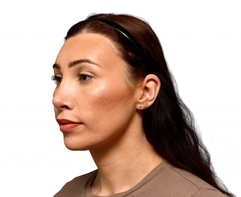 Profile view of a woman with brown hair, wearing a black headband and small stud earrings, neutral expression.
