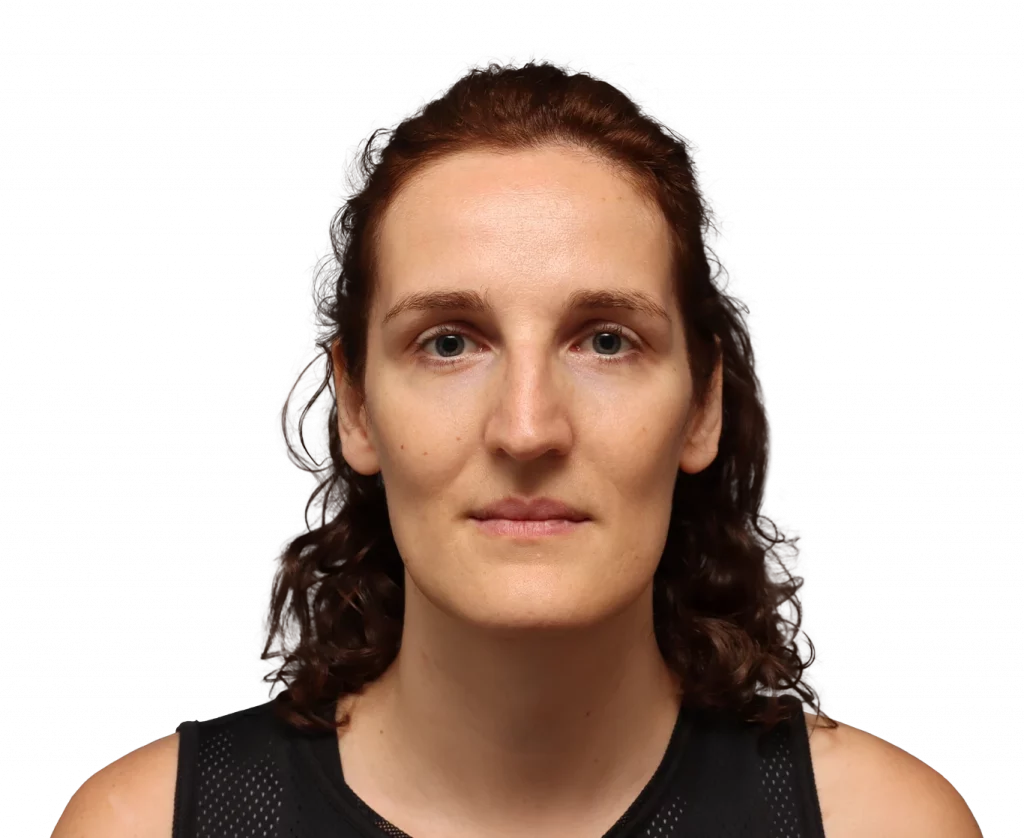 Close-up portrait of a woman with brown hair and blue eyes, wearing a black athletic top.