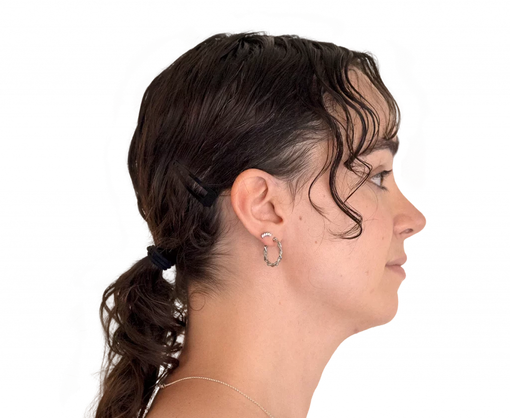 Side profile of a woman with dark brown hair tied back, wearing a hoop earring and a small barrette at the hairline