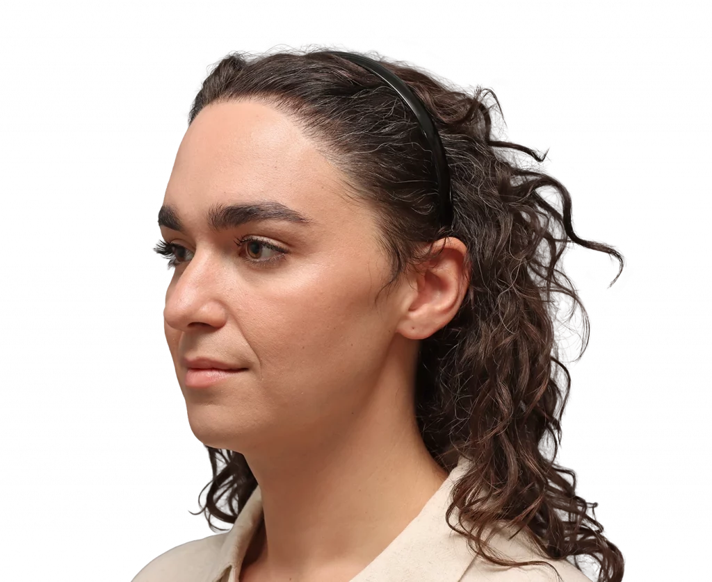 Portrait of a woman with dark hair pulled back by a black headband, looking to the left in neutral lighting.