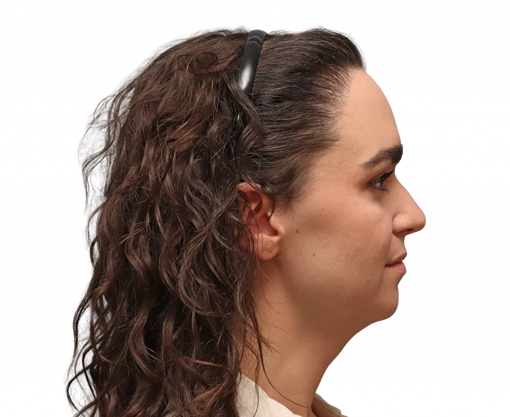 Profile view of a woman facing right, with dark brown wavy hair held back by a black hair clip.