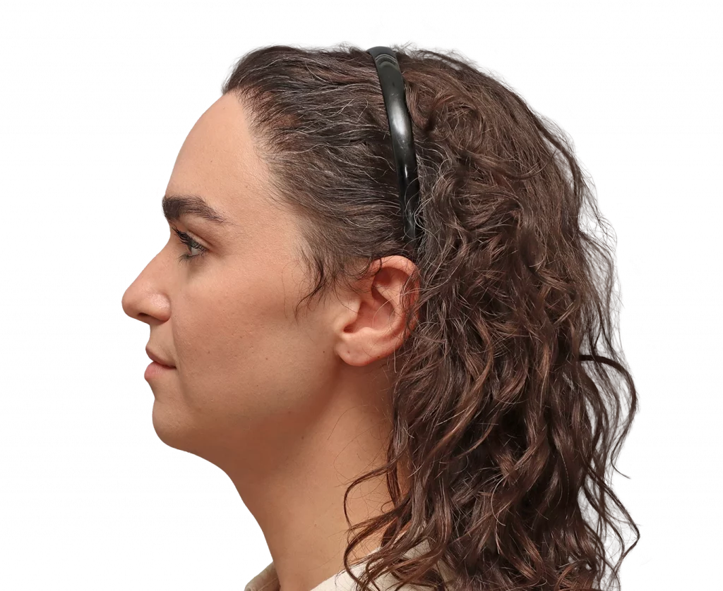 Profile view of a woman with wavy brown hair wearing a black headset over her ears