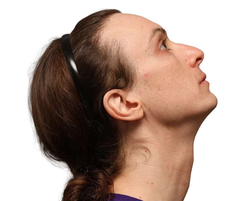 Profile view of a woman looking upward, brown hair tied back, sunglasses resting on her head