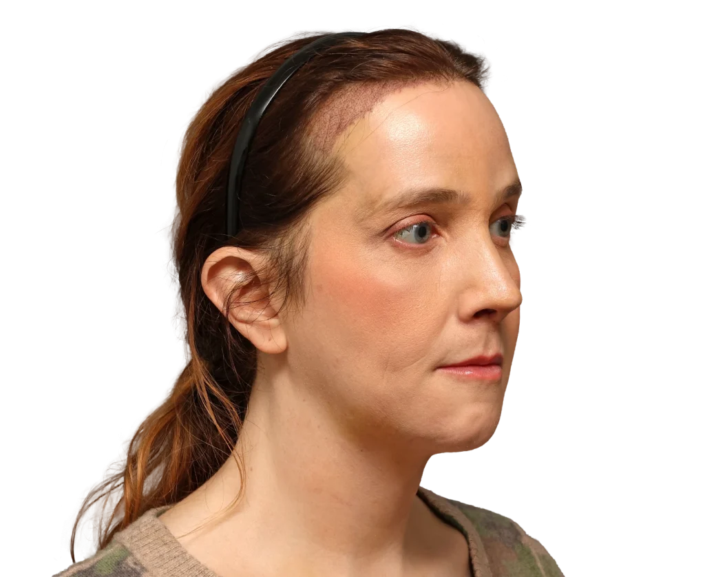 Side profile of a woman with a black headband, looking to the right, wearing natural makeup and a camo sweater.