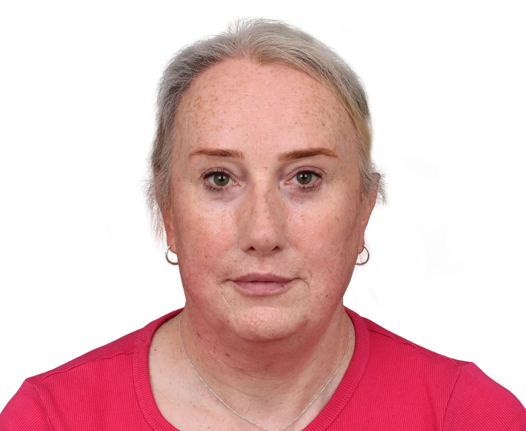 Close-up of a middle-aged woman with short gray hair, wearing a pink top, with a neutral expression.