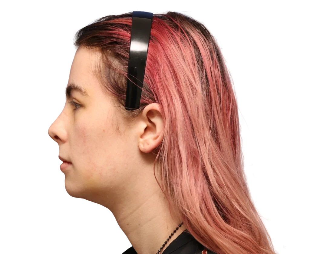 Profile view of a person facing left with pink-dyed hair and a black headband