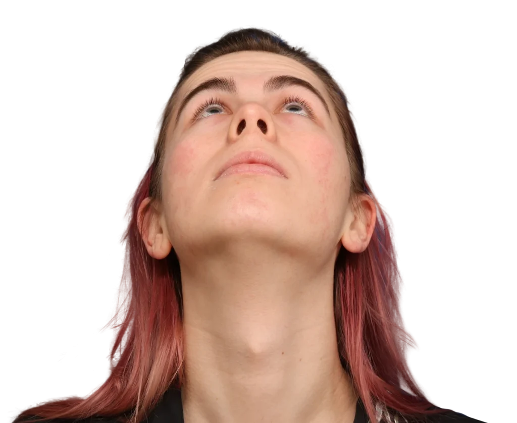 Person tilting head back and looking upward, hair dyed pink at the ends, against a black background.