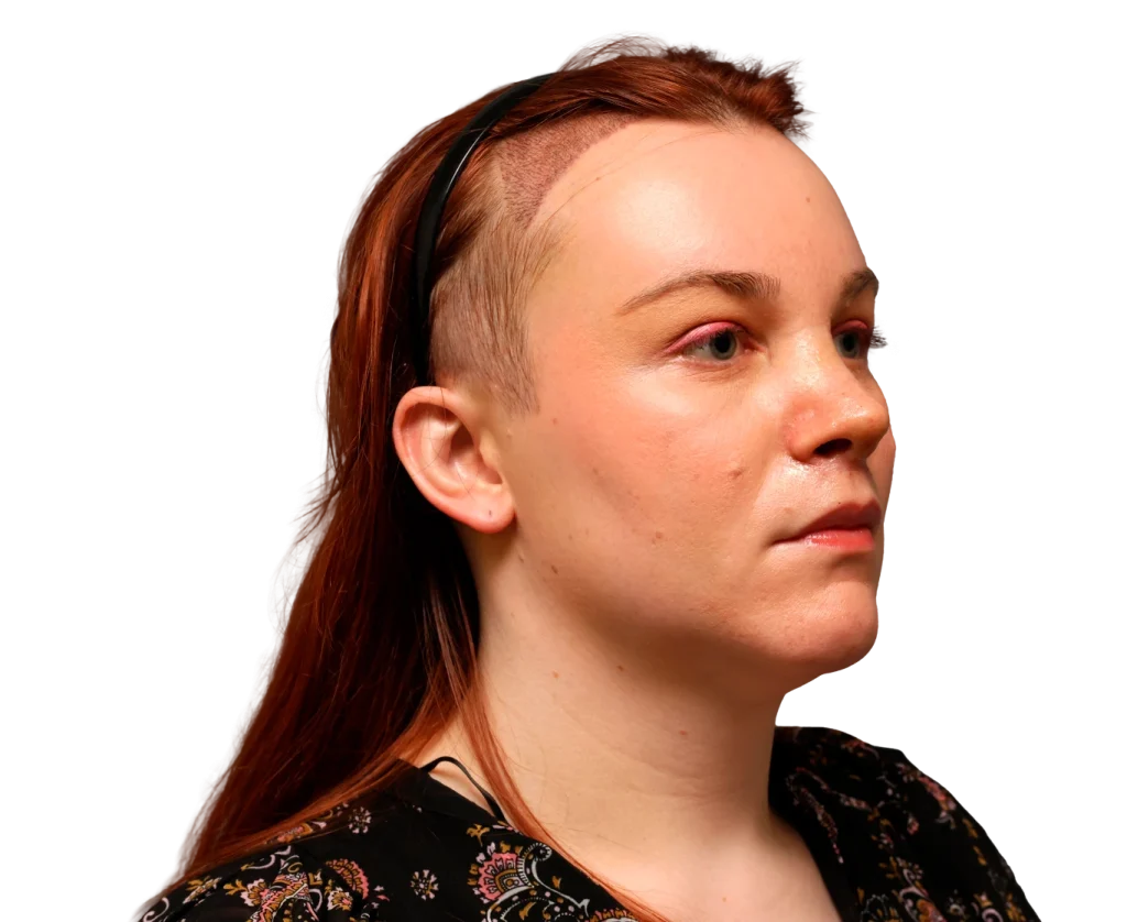 Side-profile portrait of a woman with red hair, wearing a black headband, and a floral-patterned top.