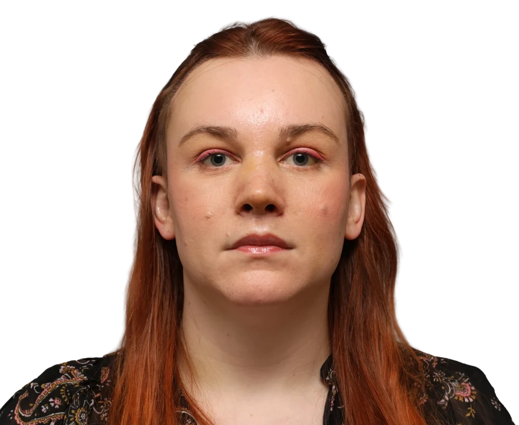 Close-up portrait of a woman with red hair and pink eyeshadow, facing the camera.