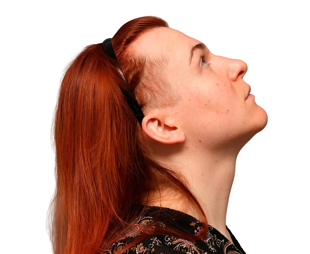 Profile view of a person with red hair looking upward, wearing a patterned shirt and a black hairband