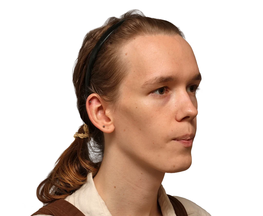 Side profile of a young woman with light brown hair tied back, wearing a black headband and beige top; neutral expression against a plain backdrop.