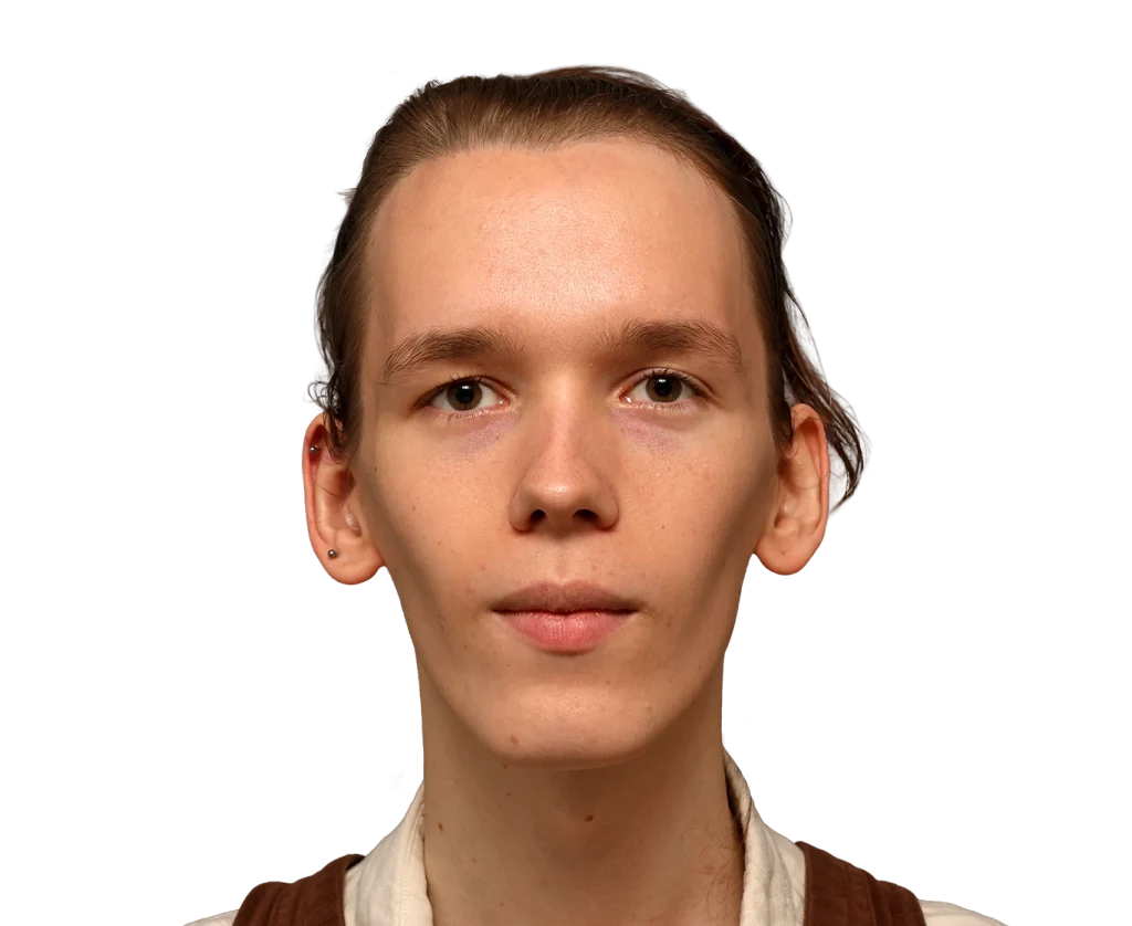 Close-up portrait of a young person facing the camera with a neutral expression, light skin, brown hair pulled back, wearing brown overalls.